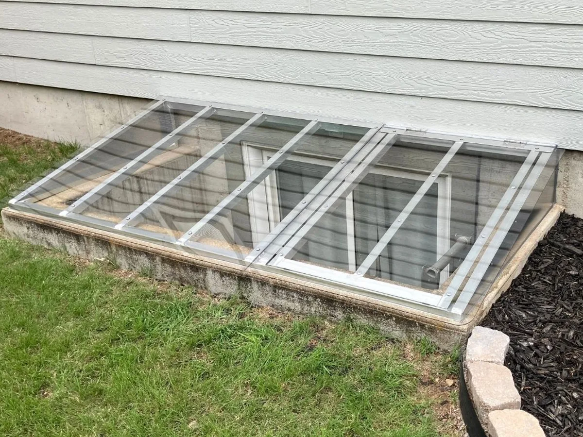 Window well cover installed on home with landscaped yard